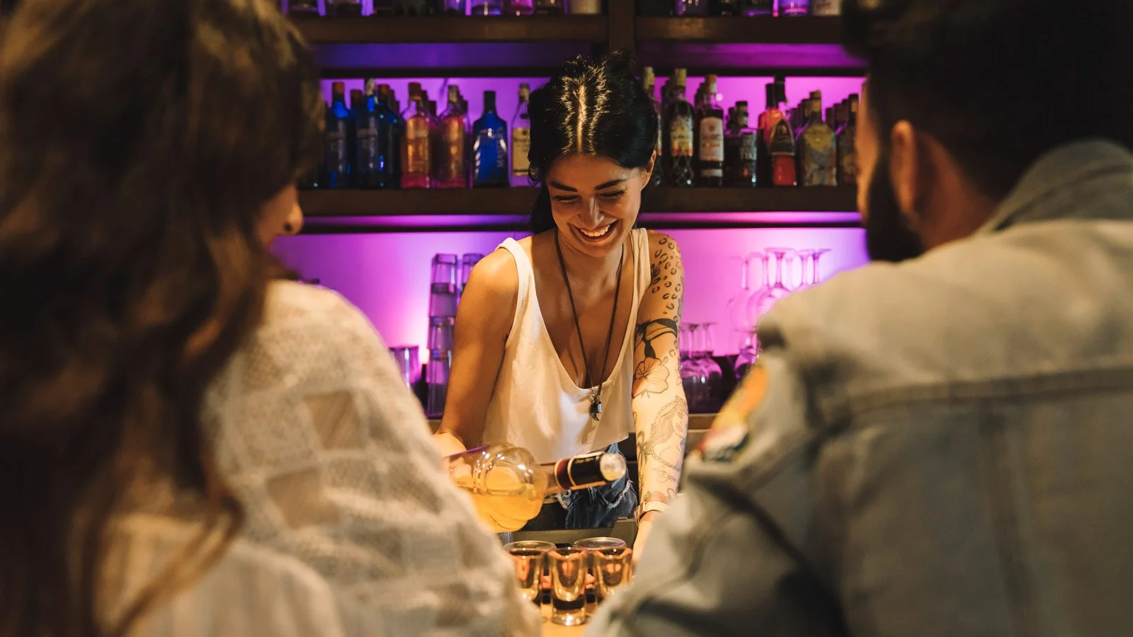 Female bartender making cocktails for couple