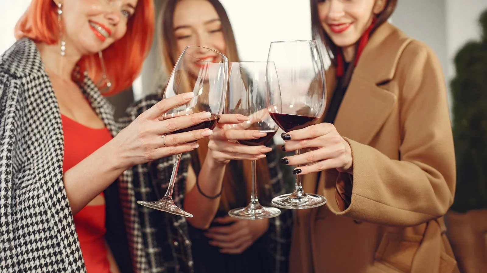 Young laughing friends drinking red wine from glass outside.